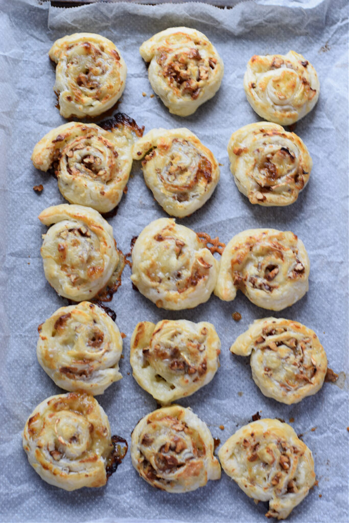 Baked puff pastry pinwheels on a baking tray.