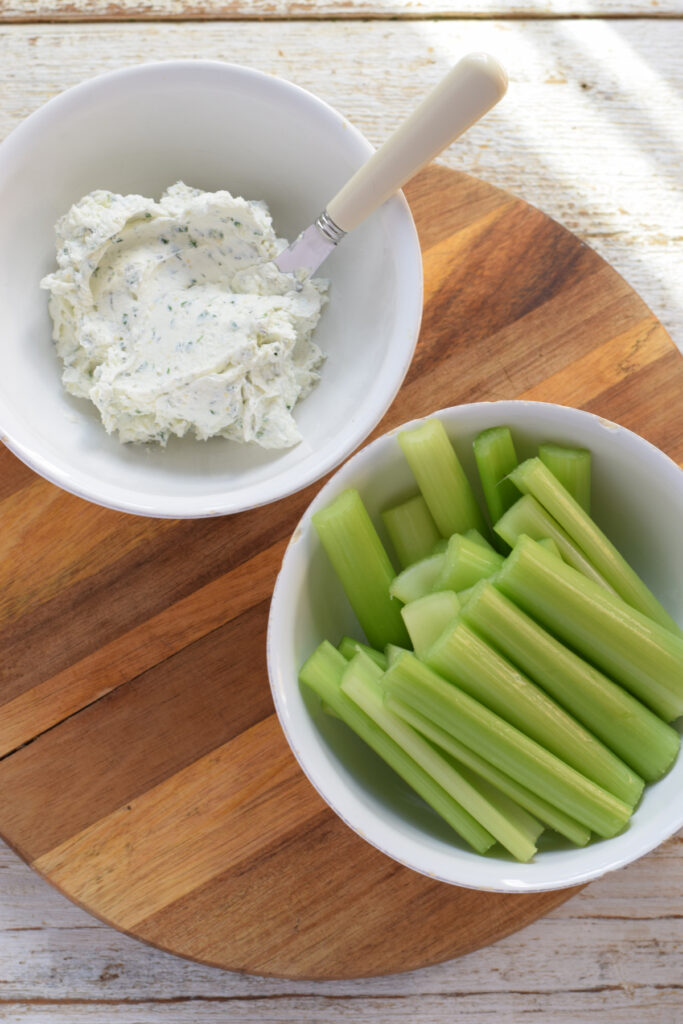 Celery and dip on a wooden board.