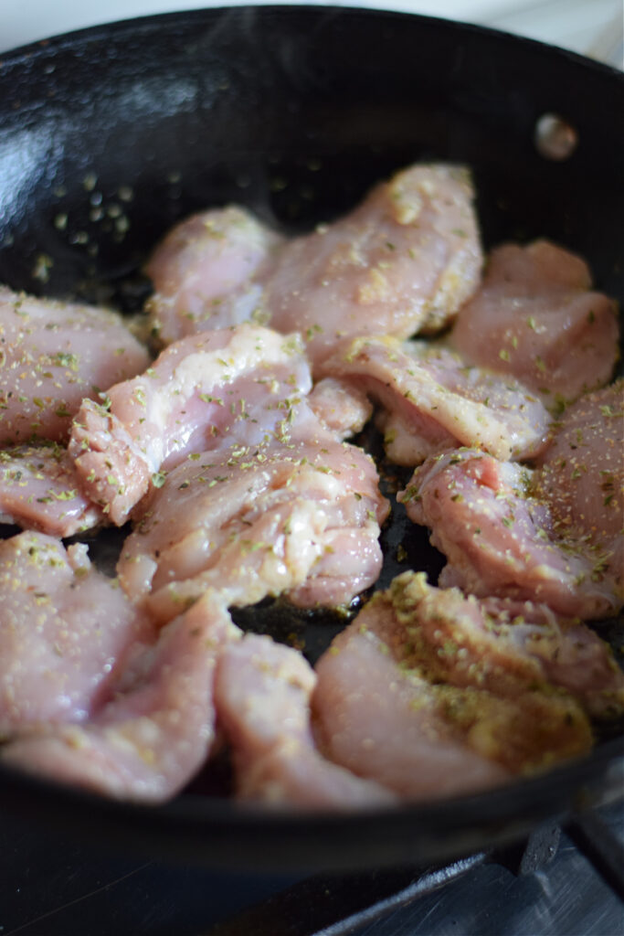 Browning chicken in a cast iron skillet.