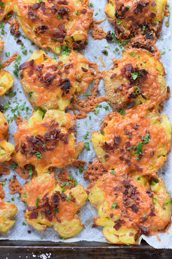 Close up of smashed potatoes on a baking tray.