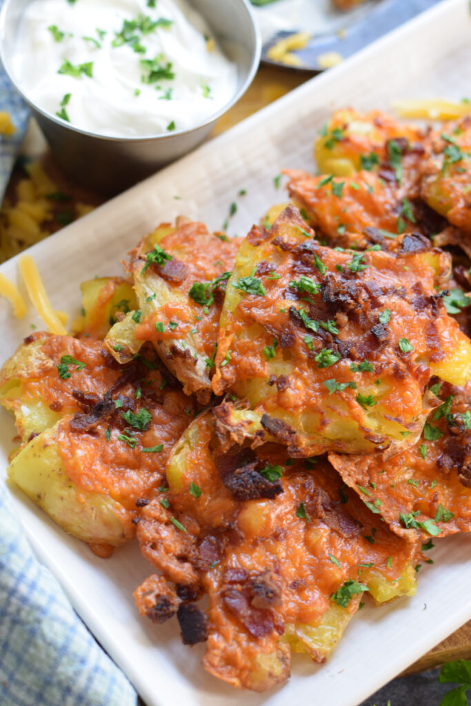 Close up of smashed potatoes on a white plate.