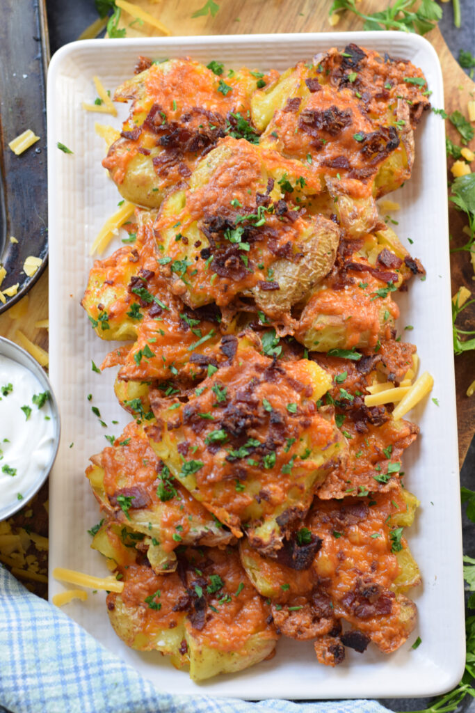 Bacon cheese potatoes on a white serving plate.