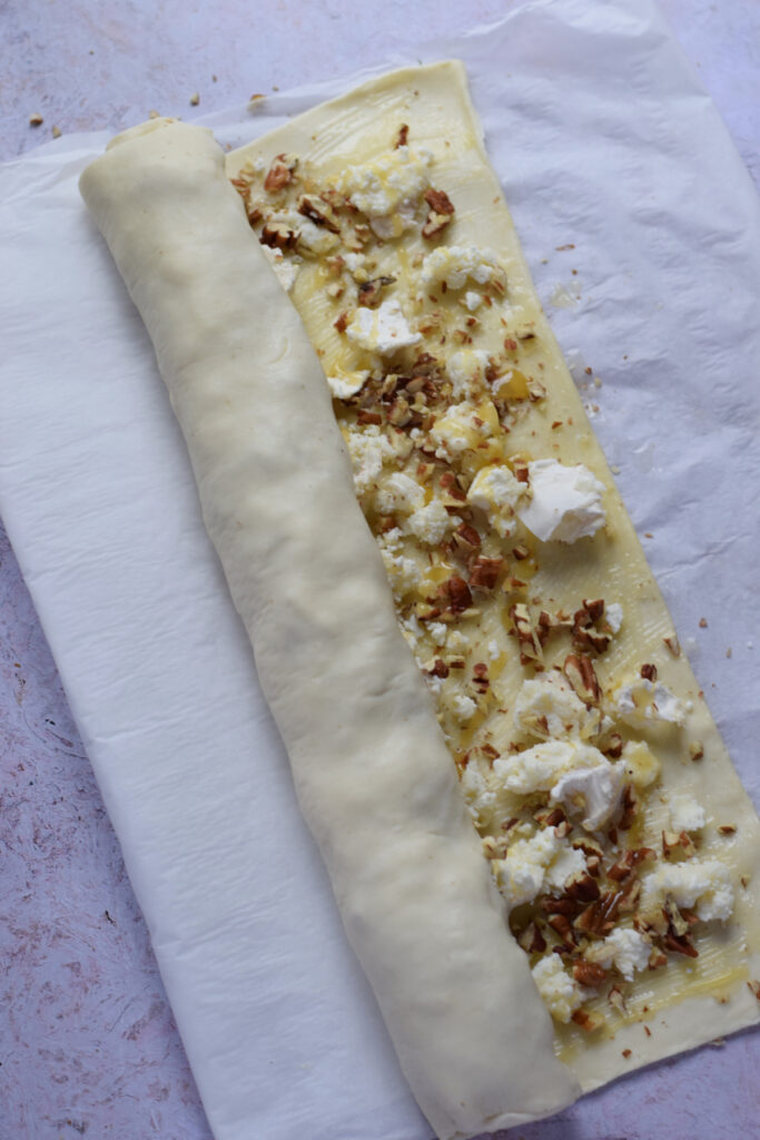 Rolling up puff pastry with nuts and cheese.