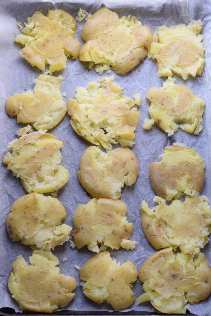 Smashed potatoes on a baking tray.