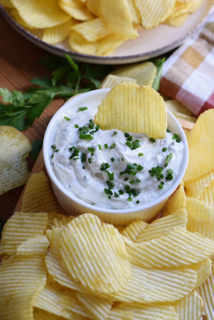 Chive din in a bowl with chips on the side.