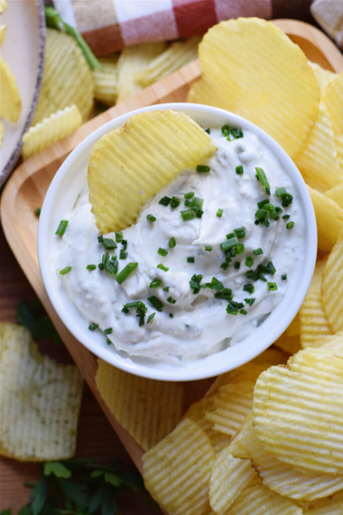 Chive dip in a white bowl and chips.