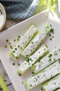 Close up of stuffed celery on a white plate.