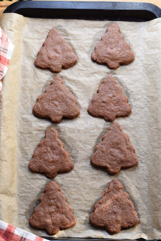 Baked Christmas tree shortbread on a baking tray.