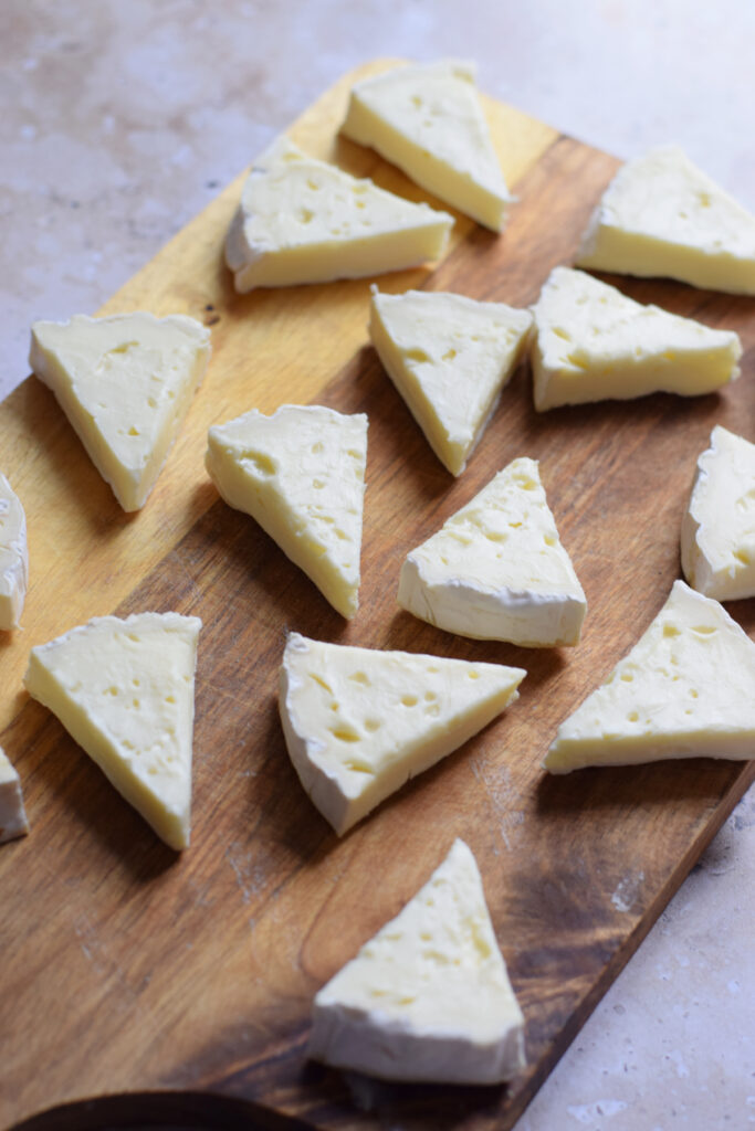 Cheese cut into wedges on a wooden board.