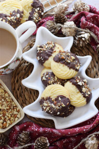 Chocolate dipped whipped shortbread cookies in a white serving plate.