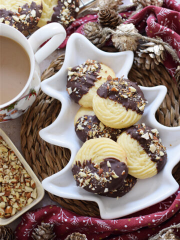 Chocolate dipped whipped shortbread cookies in a white serving plate.