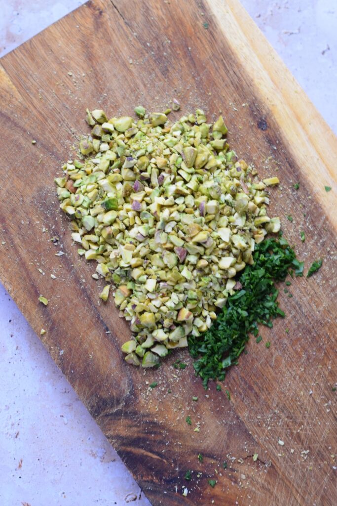 Chopped parsley and pistachios on a board.