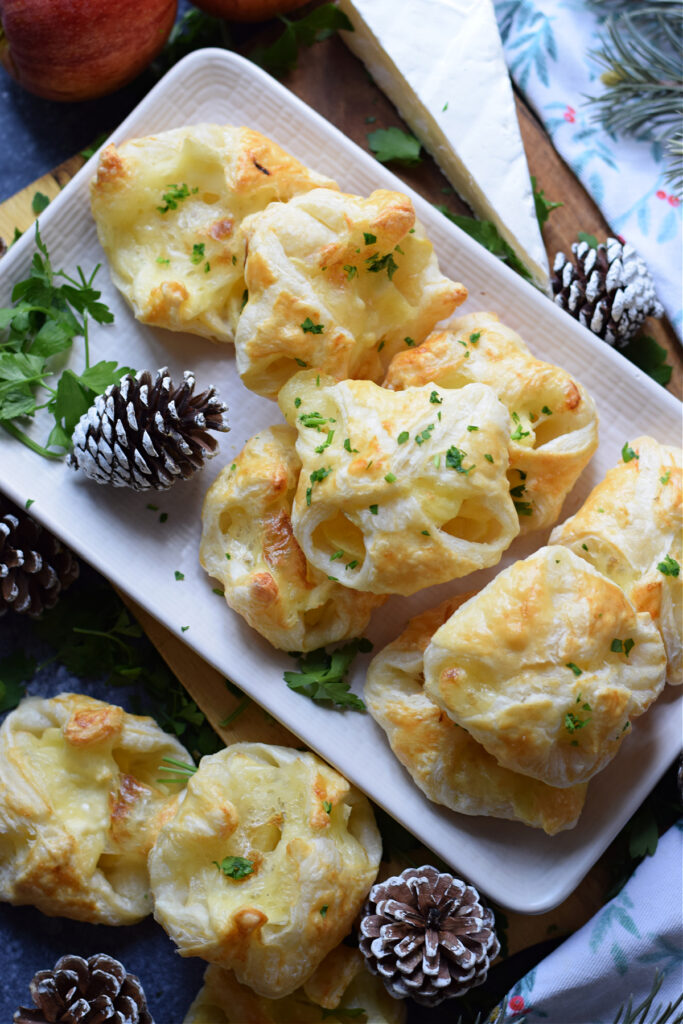 Brie and apple pastry bites on a white plate.