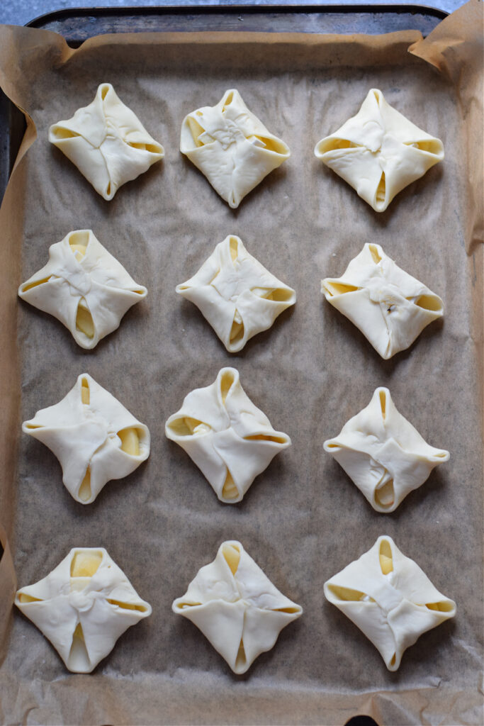 Ready to bake puff pastry appetizers on a baking sheet.