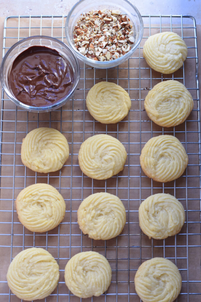 Shortbread cookies on a wire rack with chocolate and nuts.