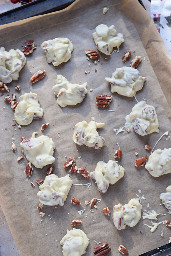 White chocolate pecan clusters on a baking tray.