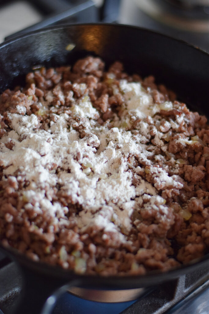 Adding flour to ground beef in a skillet