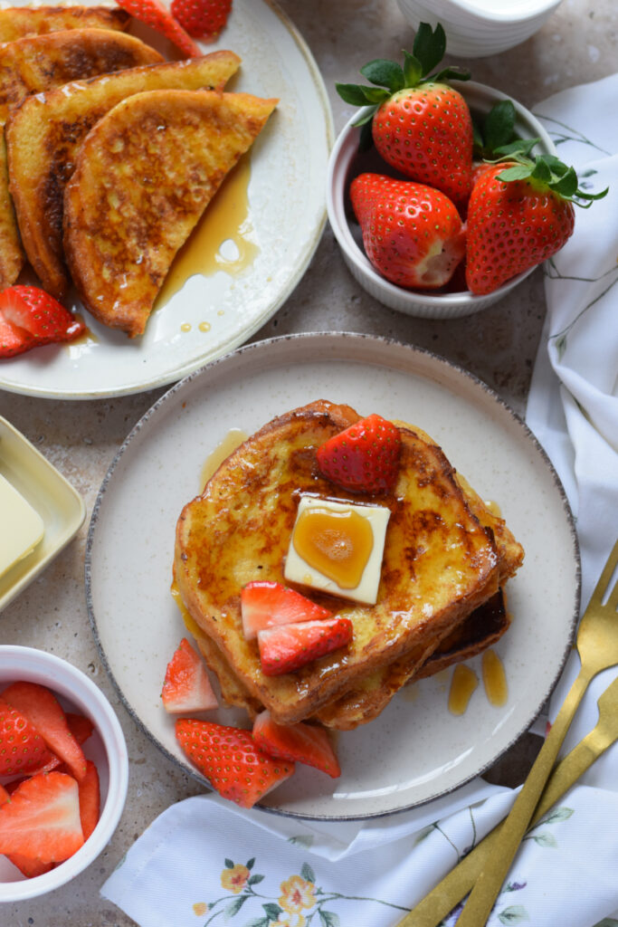 French toast on a plate with berries and butter.