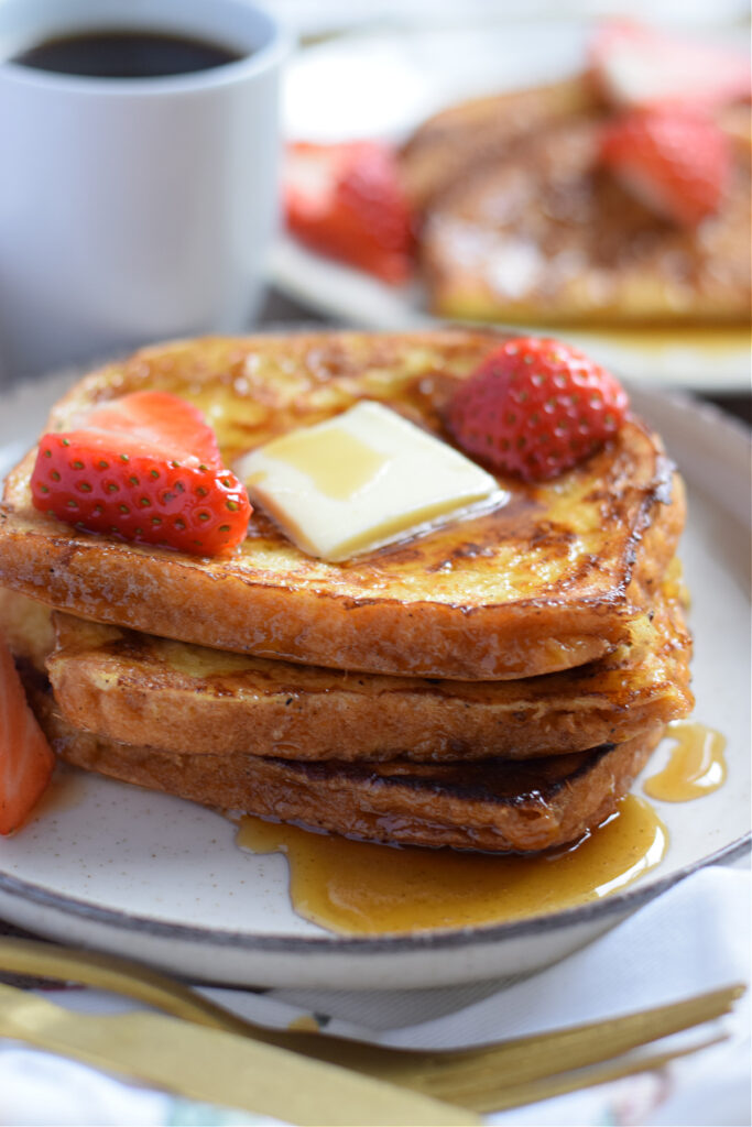 A stack of french toast with butter and berries.