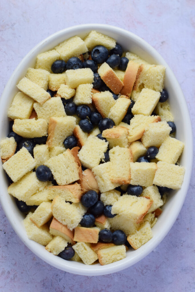 Cubed brioche bread and blueberries in a casserole dish.