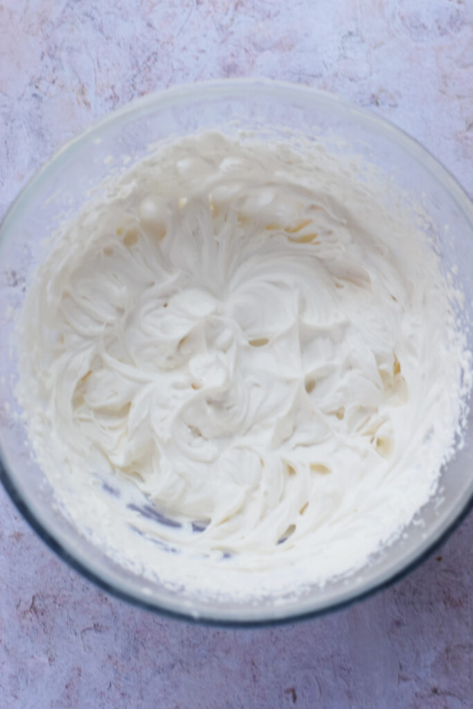 Fluffy whipped cream in a glass bowl.