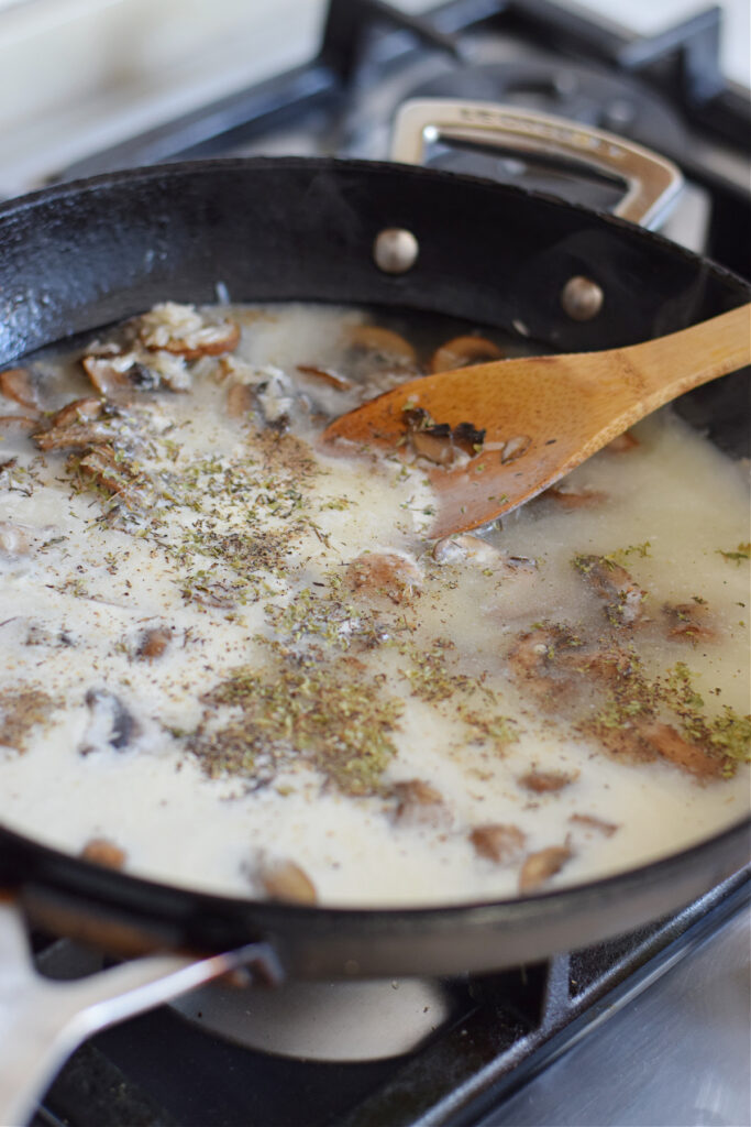 Adding broth and cream to a skillet.