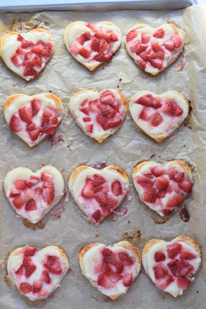 Baked puff pastry hearts with strawberries and cream cheese.