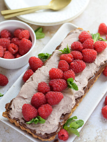 Chocolate raspberry cheesecake tart on a serving plate.