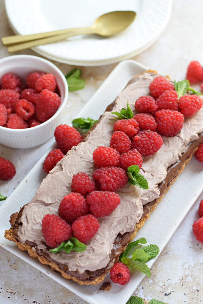 Chocolate raspberry cheesecake tart on a serving plate.