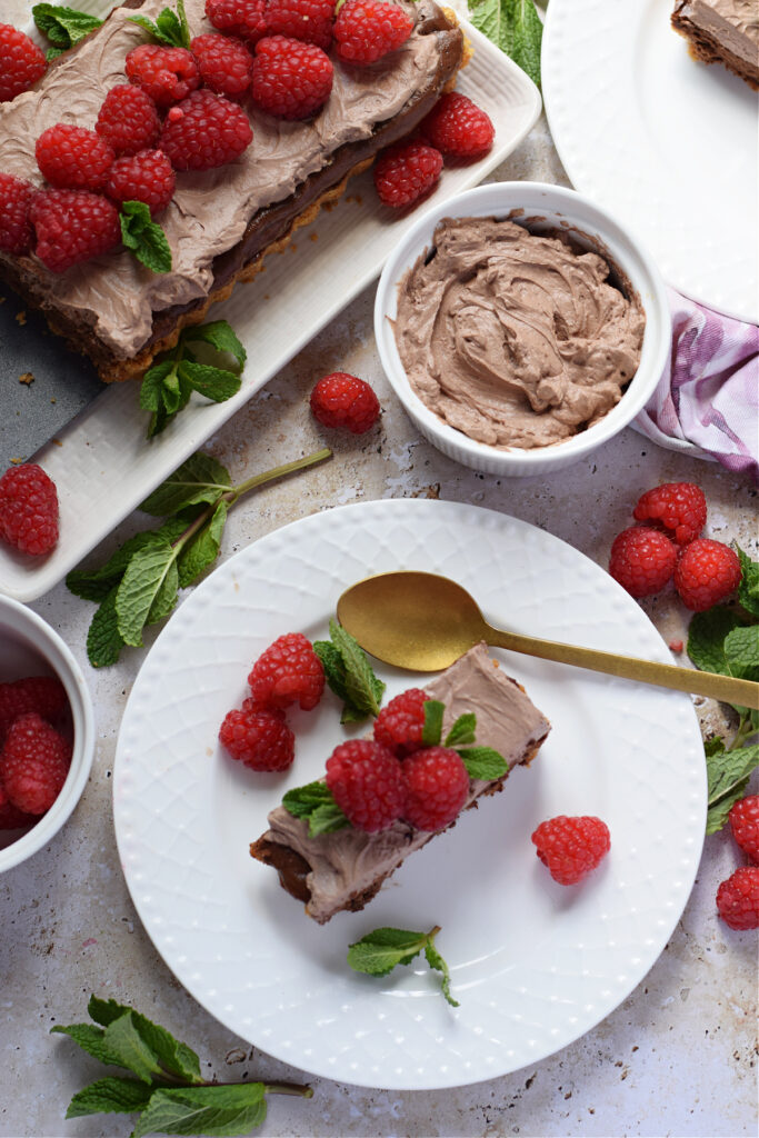 A slice of a cheesecake tart with fresh raspberries.