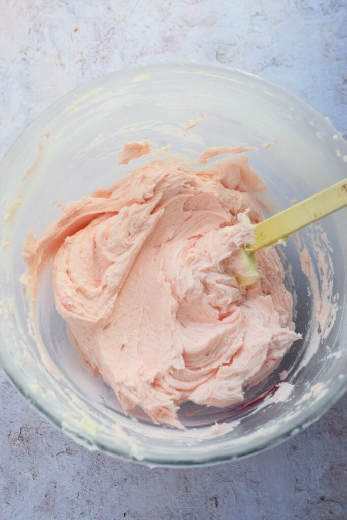 Pink frosting in a glass bowl.