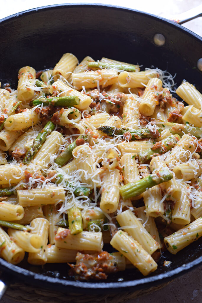 Asparagus and sun dried tomato pasta dish in a skillet.