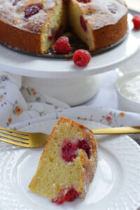 A slice of raspberry cake on a white plate.