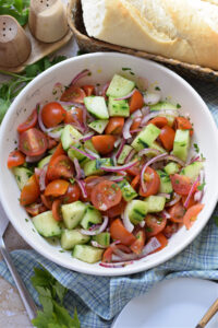 Tomato salad with cucumber in a white bowl.