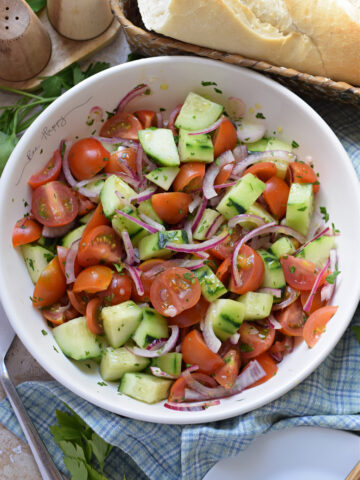 Tomato salad with cucumber in a white bowl.