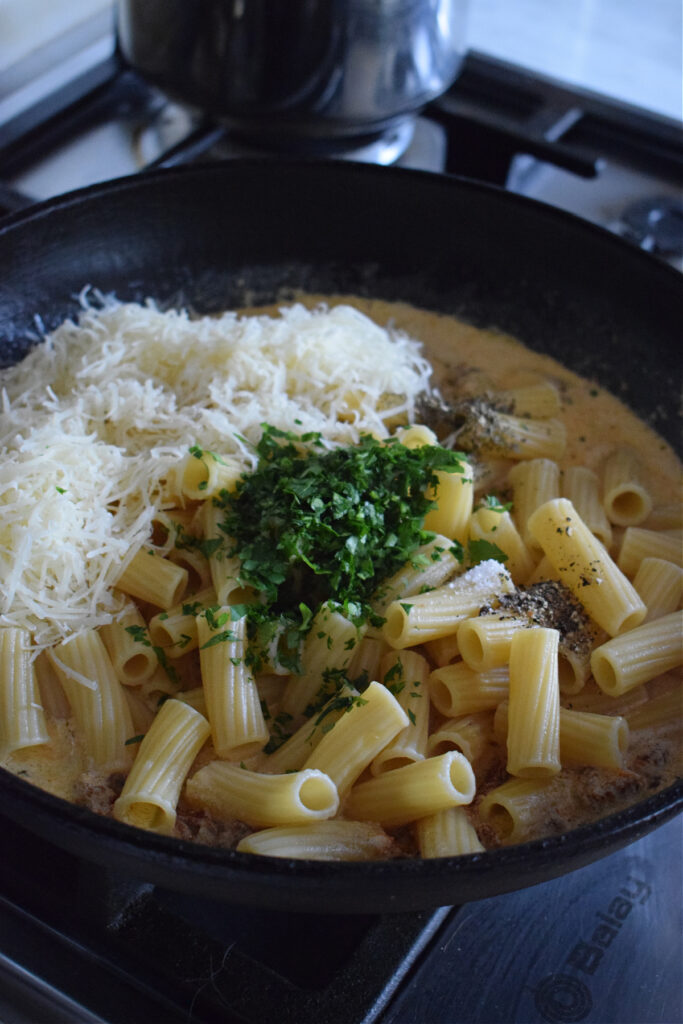Adding cheese and seasonings to pasta.