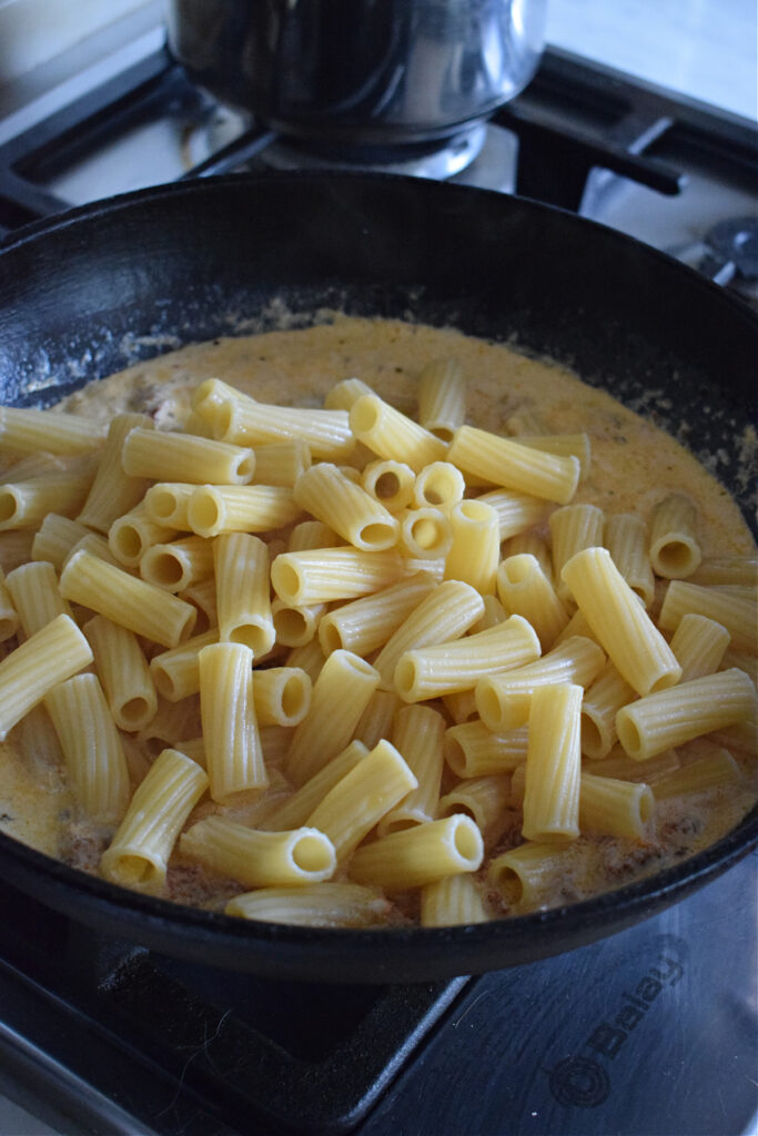 Adding pasta to a creamy sauce.