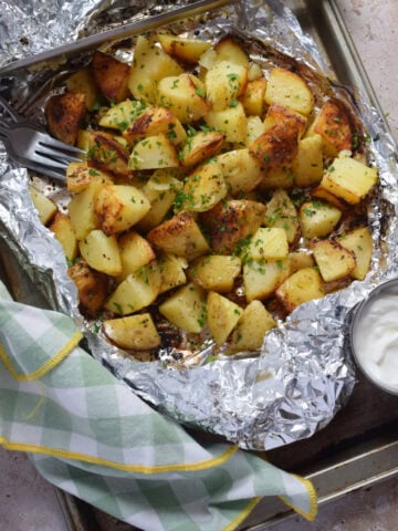 Potatoes in foil with a dip on the side.