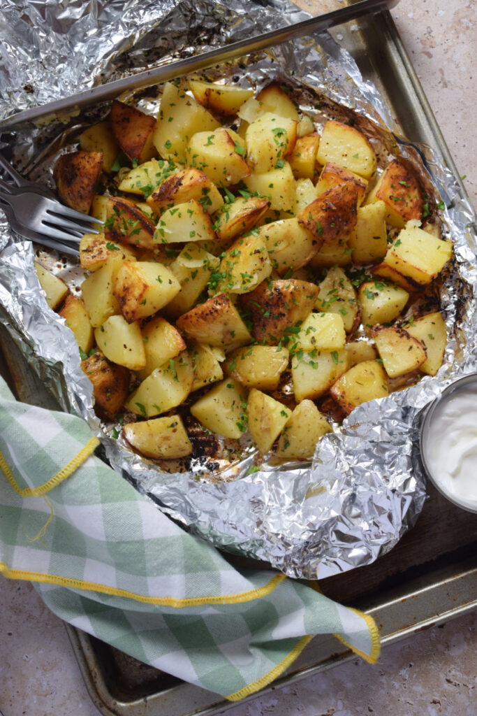 Potatoes in foil with a dip on the side.
