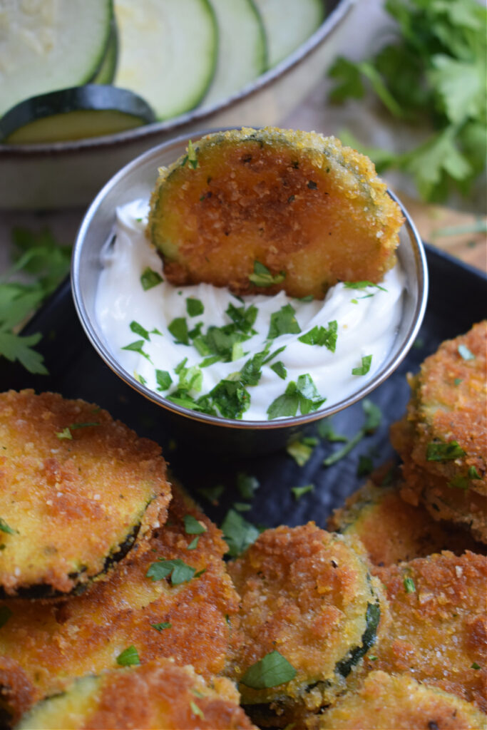 Close up of a zucchini round in a dip.