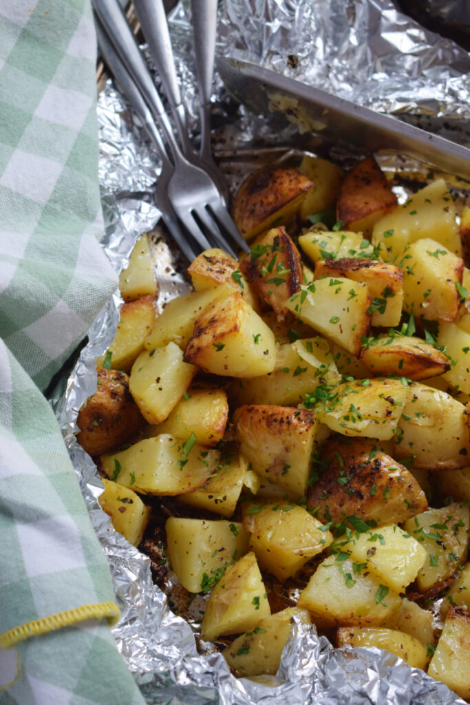 Grilled potatoes in foil with forks.