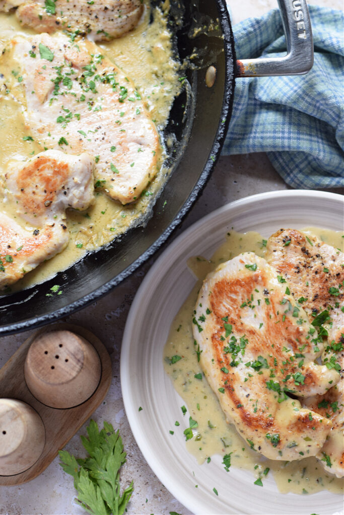 Turkey cutlets with Dijon mustard sauce in a skillet.