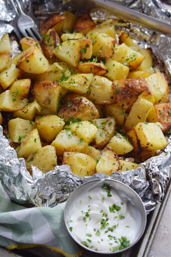 Potatoes in tin foil with a dip on the side.