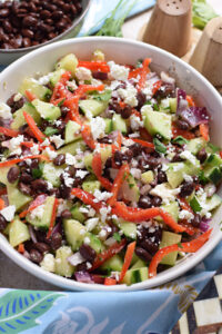 Cucumber feta and black bean salad in a white bowl.