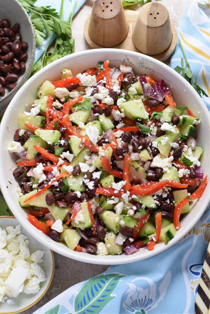 Vegetable salad with black beans in a white bowl.