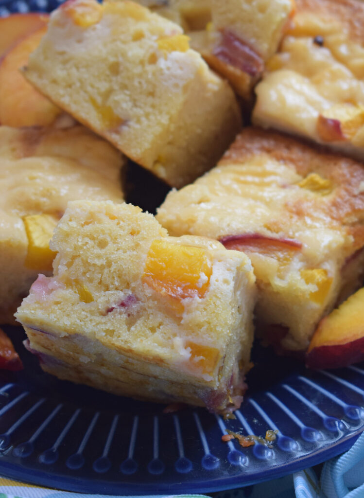 Close up of cream cheese peach cake squares on a blue plate.