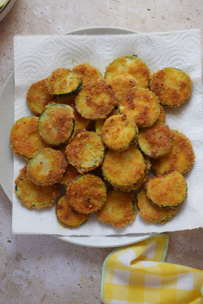 Crispy fried zucchini rounds on paper towels.
