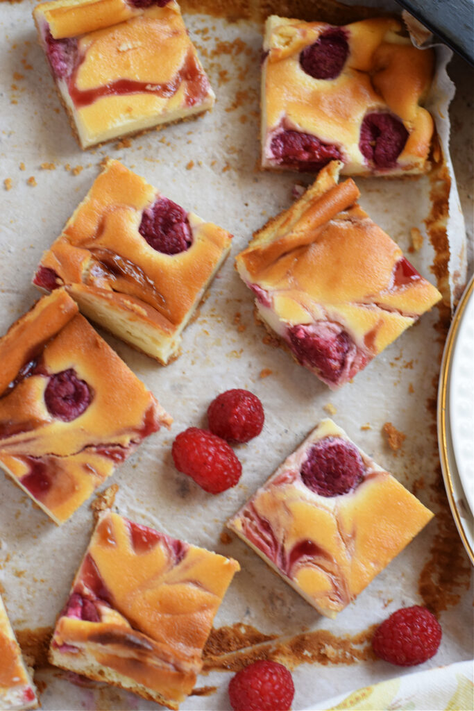 Raspberry cheese bars on parchment paper.