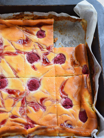 Close up of raspberry cheesecake bars in a baking pan.
