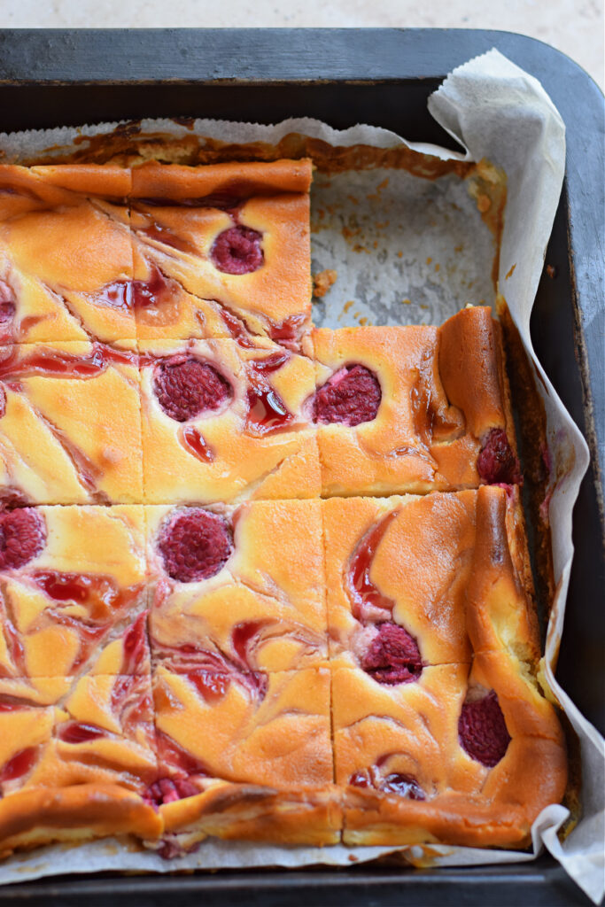Close up of raspberry cheesecake bars in a baking pan.